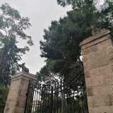 Un edificio di cui sono rimasti il muro perimetrale in pietra e il cancello di ingresso racchiuso da due colonne...